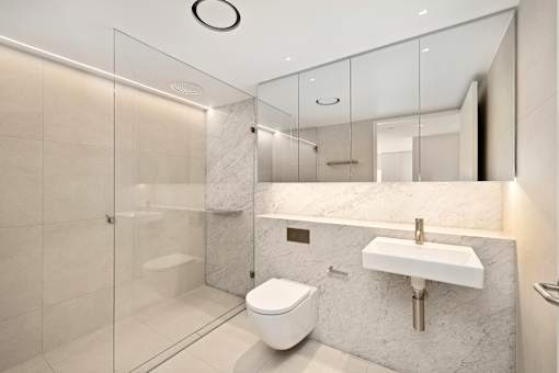 A modern bathroom with a toilet, sink, and glass shower.
