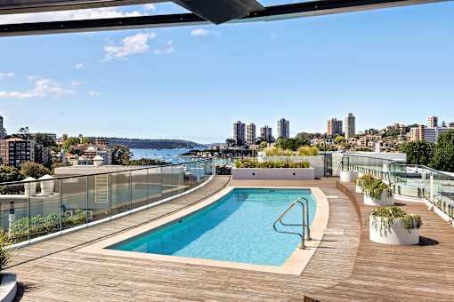 A swimming pool on a wooden deck with a cityscape in the background.