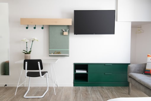 a room with a desk and a chair and a television on the wall