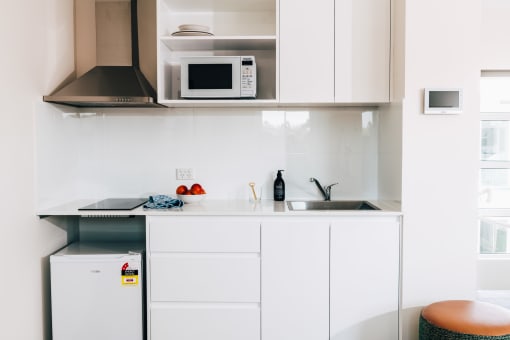 a small kitchen with white cabinets and a sink and a microwave