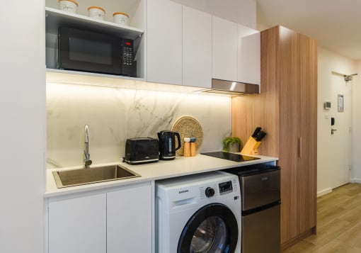 a kitchen with a washing machine and a sink and a microwave