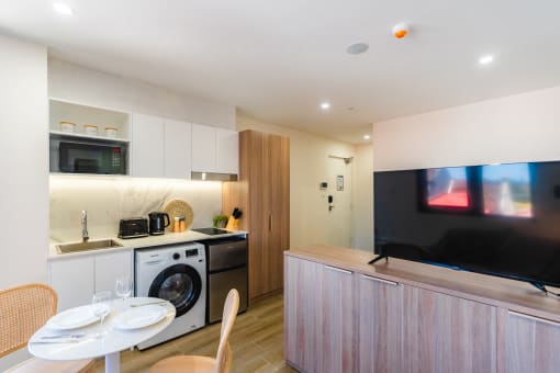 a kitchen and dining area with a washing machine and a television
