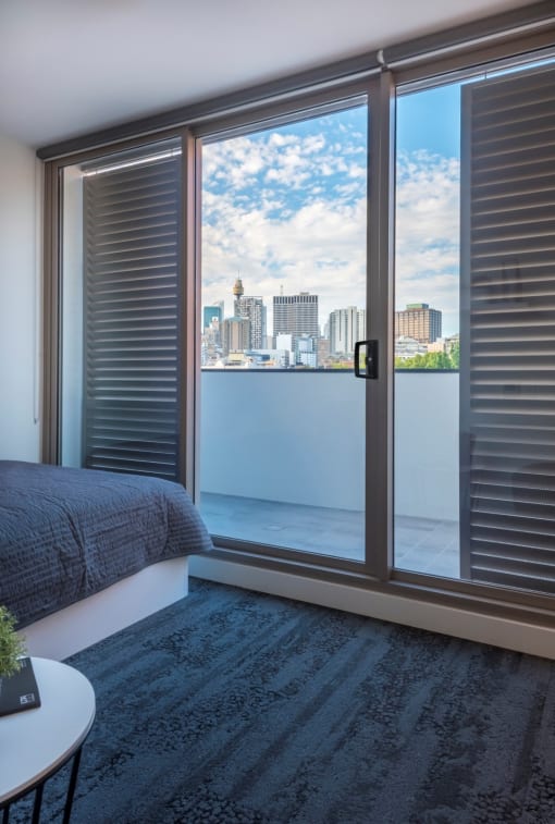 a bedroom with a balcony and a view of the city