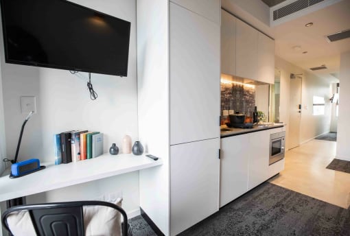 a kitchen with white cabinets and a tv on the wall