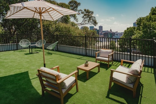 a rooftop terrace with lawn chairs and an umbrella