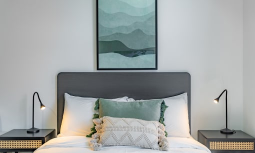 a bedroom with a bed with pillows and a painting on the wall
