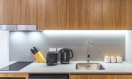 a kitchen counter with a sink and a kettle and a coffee maker