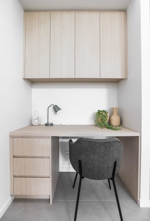 a desk and a chair in a room with wooden cabinets