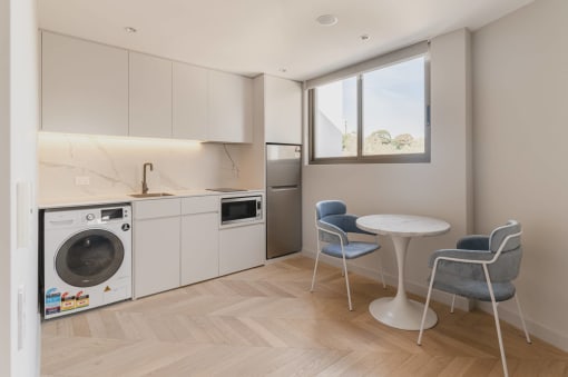 a kitchen with a washing machine and a table with chairs