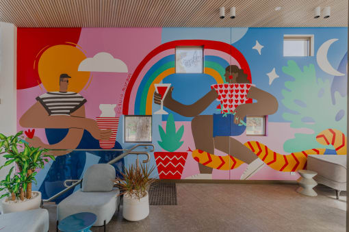 a colorful mural in a room with couches and potted plants