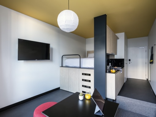 a small room with a black table and a kitchen and a bed