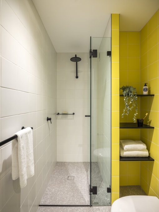 a bathroom with yellow tiles and a glass shower door