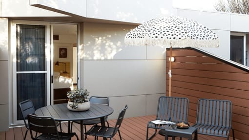 a small patio with a table and chairs and an umbrella