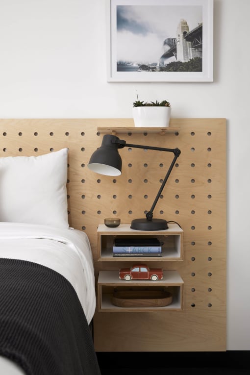 a bed with a wooden headboard and a shelf with a lamp and a clock