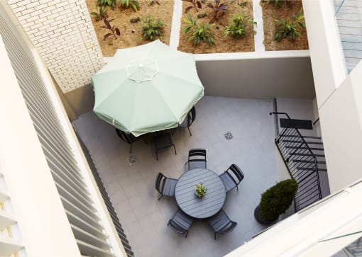 a patio with a table with a green umbrella