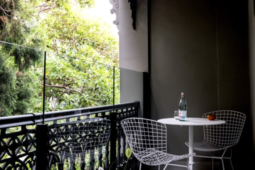 a table and chairs on a balcony with a bottle of wine