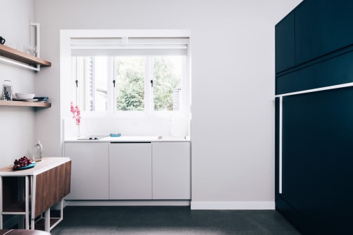 a kitchen with white cabinets and a window and a black refrigerator