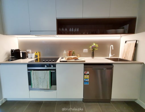 a small kitchen with white cabinets and a stainless steel dishwasher