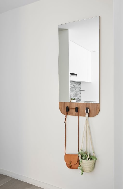 a mirror hanging on a wall with two hanging bags