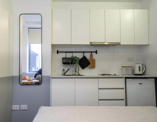 a kitchen with white cabinets and a mirror on the wall