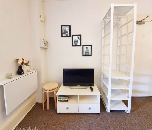 a living room with a tv and a white shelf