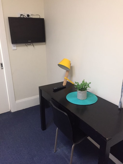 a small desk with a lamp and a tv on the wall