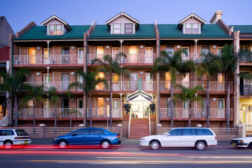 a building with palm trees and cars parked in front of it