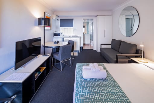 a hotel room with a bed and a television and a kitchen