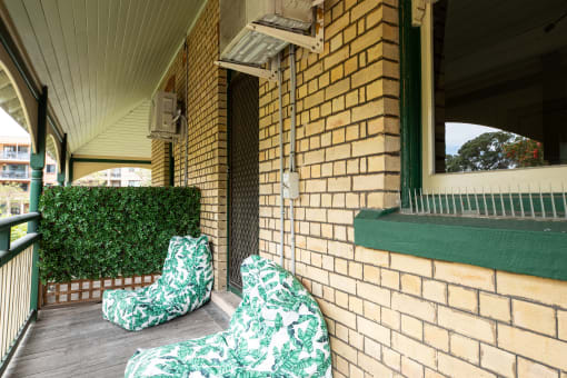 two chairs sitting on a porch next to a brick building