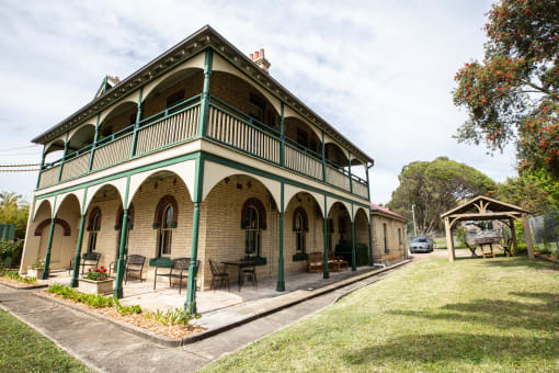 a large green and brick building with a porch and awning