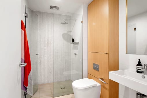 a bathroom with a shower and a wooden floor and white walls