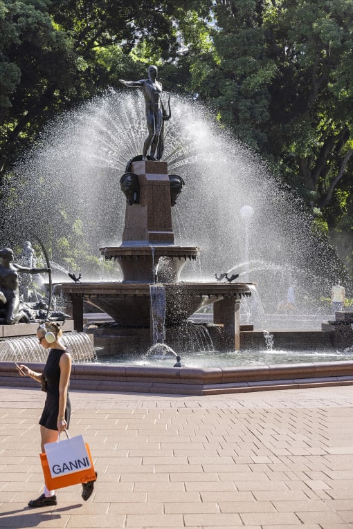 a woman walking in front of a water fountain