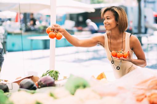 a woman holding tomatoes at a fruit and vegetable market