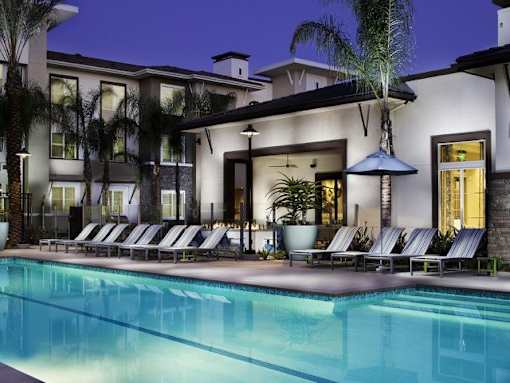 a swimming pool with rows of lounge chairs in front of a building