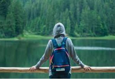 a person with a backpack is standing on a pier overlooking a lake