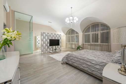 A bedroom with a large bed and a television in the corner.