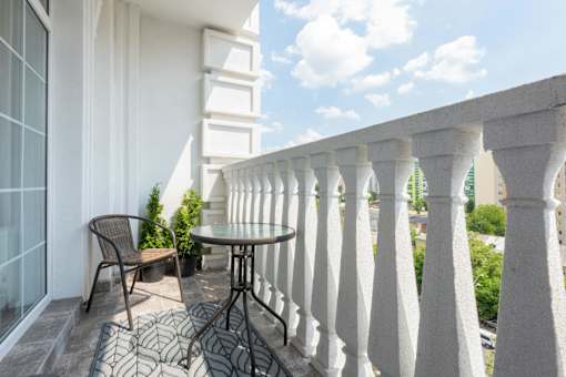 A balcony with a table and chairs overlooking a cityscape.