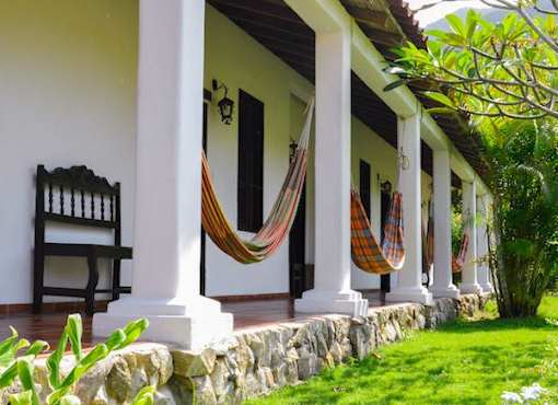 A porch with a bench and hammocks.
