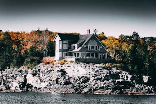 A house is built on a rocky outcrop by the water.