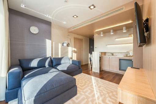 A living room with a grey sofa and a television on the wall.