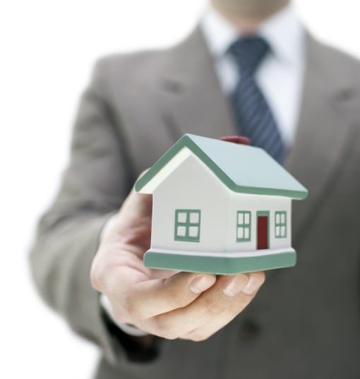a man in a suit holding a small house