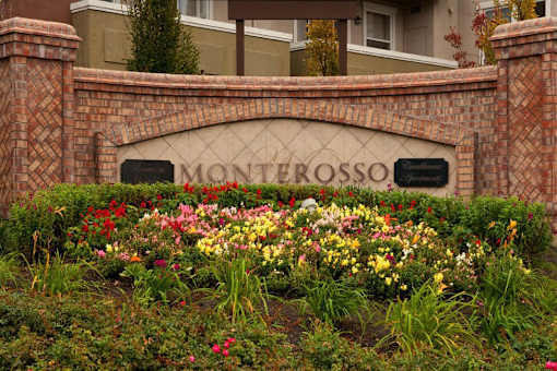 A sign that says "Monterosso" is surrounded by flowers.