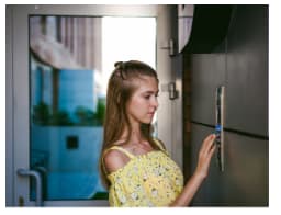 A women trying to open the apartment door with a controlled access system