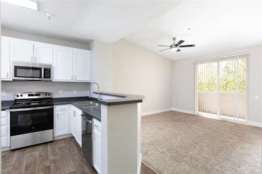 A kitchen with white cabinets and a black countertop.