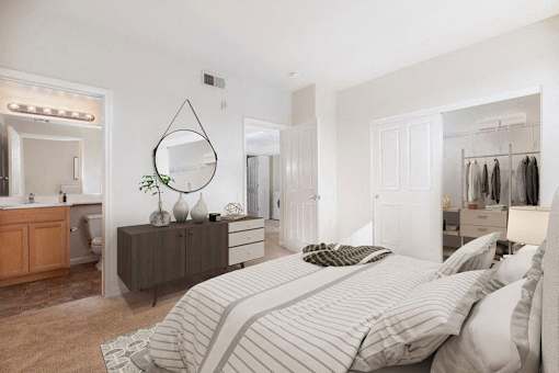 A bedroom with a large bed and a vanity with a mirror.