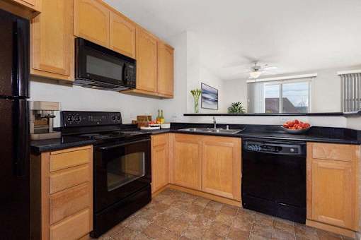 A kitchen with wooden cabinets and black appliances.