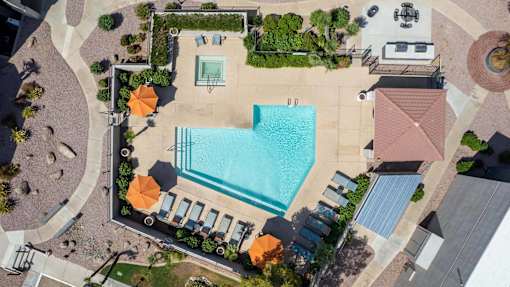 An aerial view of a pool surrounded by orange umbrellas and lounge chairs.