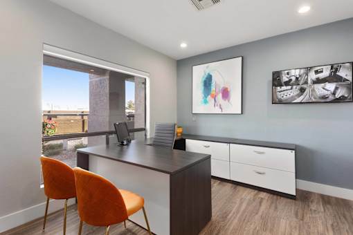 A room with a desk, chairs and pictures on the wall.