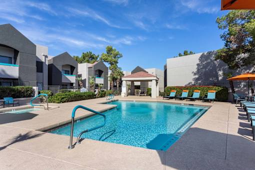 A swimming pool surrounded by lounge chairs and buildings.