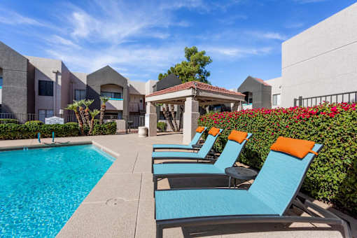 A pool area with blue chairs and a white gazebo.